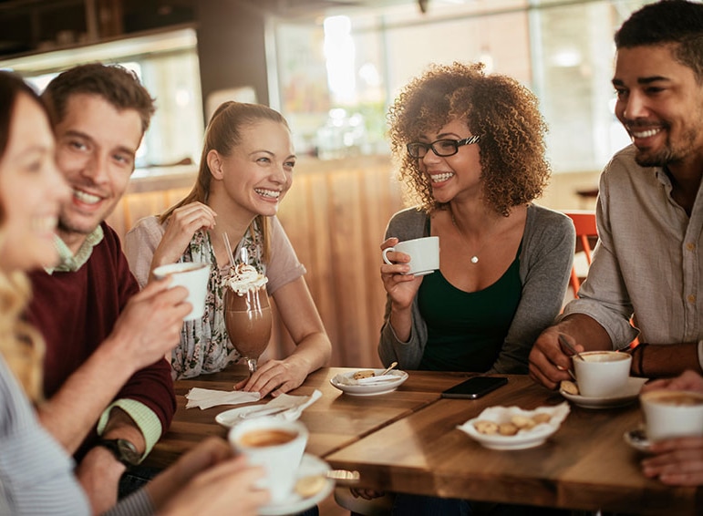 Un groupe d'amis buvant joyeusement du café autour d'une table dans un café.